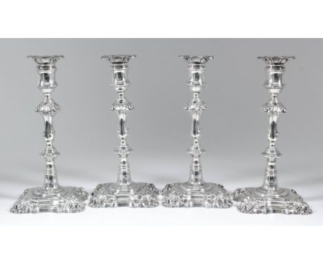 A set of four George IV silver pillar candle sticks of "mid 18th Century" design, with turned and square knopped columns, con