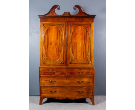 A George III gentleman's mahogany wardrobe, the upper part with moulded scroll pediment, carved leaf paterae and dentil corni