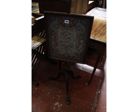 A 19th century mahogany pole screen, with a glazed needle work screen depicting a Phoenix amongst flowers,on a tripod base. 1