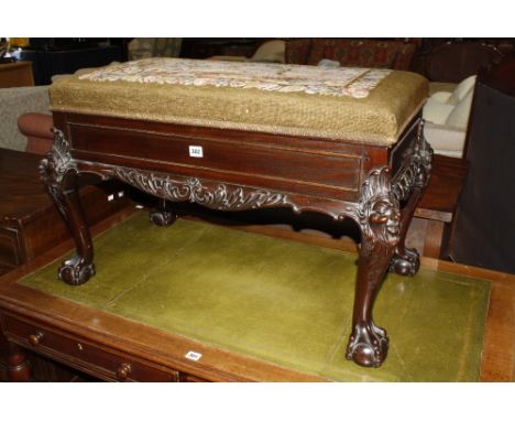 A mahogany 19th century duet piano stool with needle point hunting scene to the hinged seat raised on masked carved cabriole 