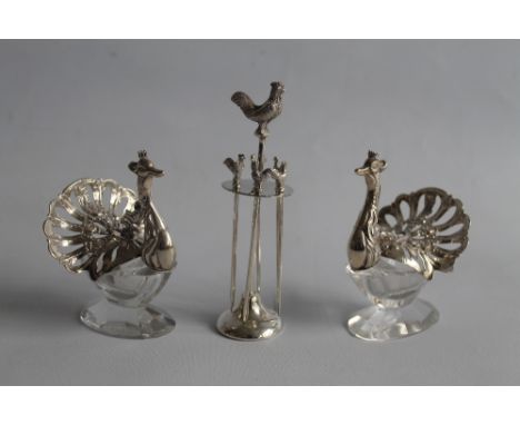 TWO CONTINENTAL WHITE METAL & GLASS SALTS, in the form of peacocks, along with a small plated cocktail stick stand with cocke