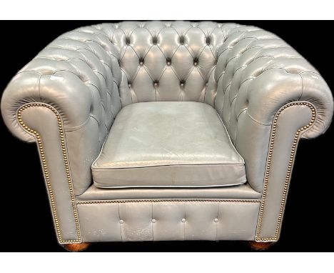 Chesterfield tub chair, covered in a duck egg blue button upholstery finished with a brass nail head trim, raised on bun feet