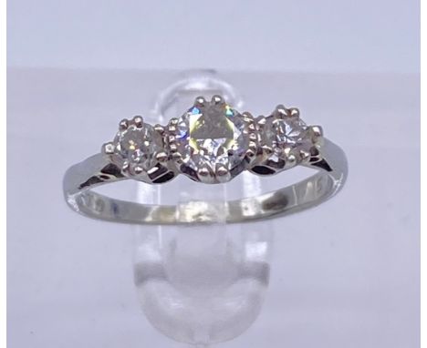 A three stone diamond ring The graduated diamonds claw set and on a white metal shank Ring size: J/KWeight: 1.80g