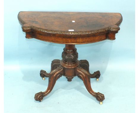 A Victorian walnut fold-over card table, the shaped top with carved border, on turned and carved pillar and quadruped support