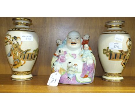 A modern Chinese ceramic seated Buddha and a pair of 20th century Satsuma vases on wooden stands.