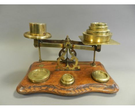 A oak mounted brass postal scale with a series of weights