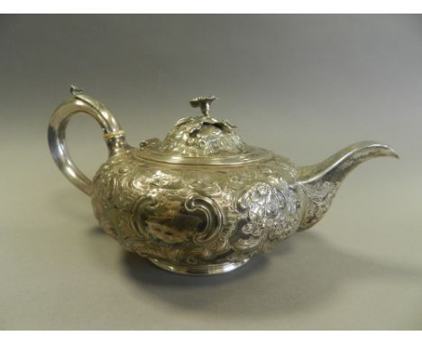 A Victorian silver teapot with embossed floral scroll decoration and cast floral finial
