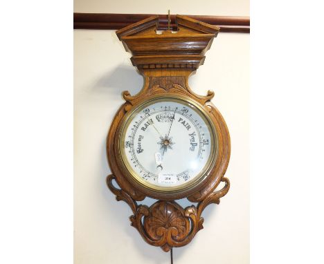 A Victorian circular wall barometer with white dial within carved oak case surmounted by an architectural pediment, 55cm high