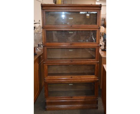 An oak Globe Wernicke five section bookcase, raised on a platform plinth, 86cm wide x 168cm high