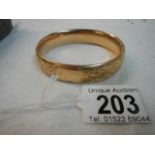 An engraved gold coloured bangle.