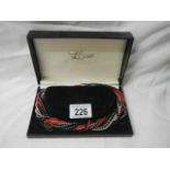 A boxed multi coloured necklace.