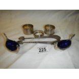Three silver napkin rings, two plated salts with blue glass linings and a pair of sugar nips.