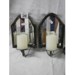 A pair of wall mounting candle holders with mirrors in back.