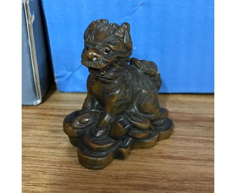 A Japanese hand carved netsuke of a foo dog signed by the artist. Measures 5cm in height 