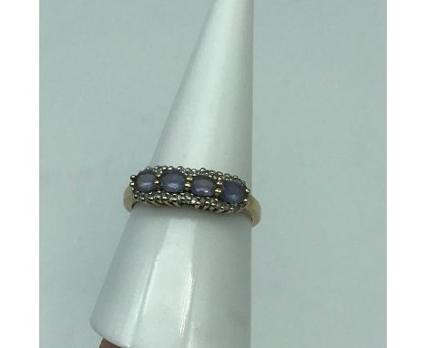 A Ladies 9ct gold ring set with 4 pale purple stones surrounded by diamond cluster. Ring size P. Weighs 2.36grams 