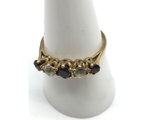 A 9ct gold ladies ring set with 3 garnets and 2 clear stones, Ring size R. Weighs 2.57grams 