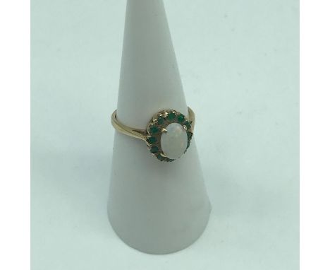 A Lovely example of a ladies 9ct gold ring set with a large single opal and emerald cluster. Weighs 2.10grams 