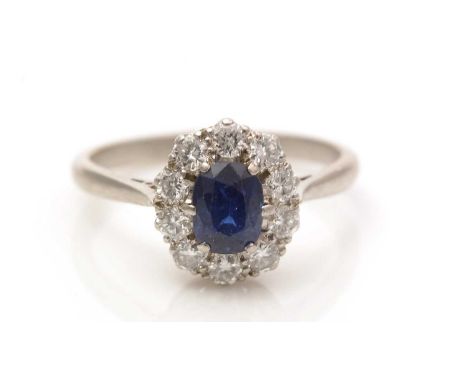 A sapphire and diamond cluster ring, the oval facet cut sapphire 5.7 x 3.6 x 3.3mm, surrounded by ten brilliant-cut diamonds 