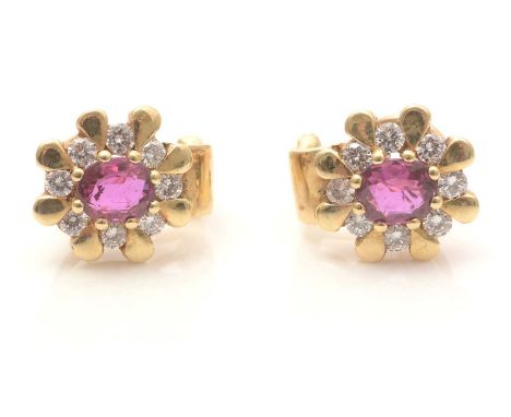 A pair of ruby and diamond cluster earrings, each oval facet-cut ruby measuring 6.0 x 5.3mm (depth unobtainable), surrounded 