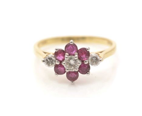 A ruby and diamond ring, centered by a brilliant-cut diamond surrounded by a cluster of circular facet-cut rubies and flanked