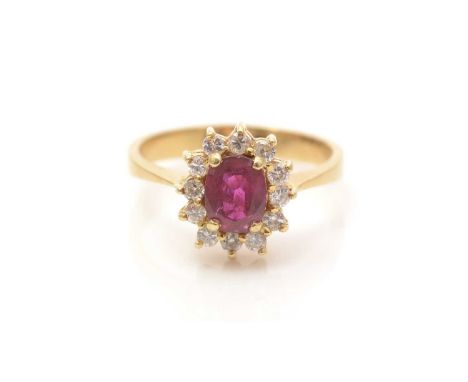 A ruby and diamond cluster ring, the oval facet-cut ruby measuring 6.2 x 4.8 x 2.7mm, surrounded by twelve brilliant-cut diam