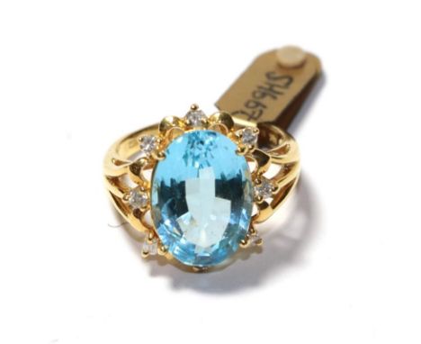 An 18 carat gold blue topaz and diamond cluster ring, the oval cut blue topaz within a spaced border of round brilliant cut d