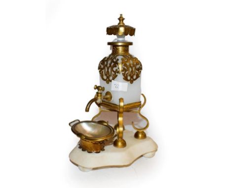 A brass mounted opaline glass scent decanter, the bottle of square section, with openwork foliage mounts, tap and stopper on 