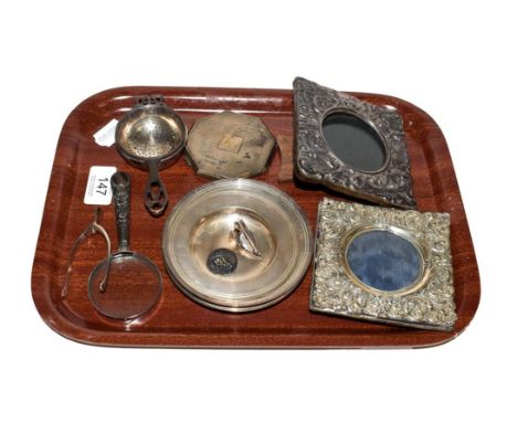 A collection of silver items to include two repousse easel photograph frames, four pin dishes, an Art Deco powder compact, a 