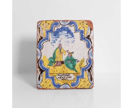 A glazed earthenware tile, 18th century, probably Samarkand, painted with two figures within a scrolled border, above a Cyril