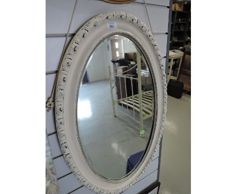A vintage mirror oval with carved wood frame and bevel edged glass painted shabby chic