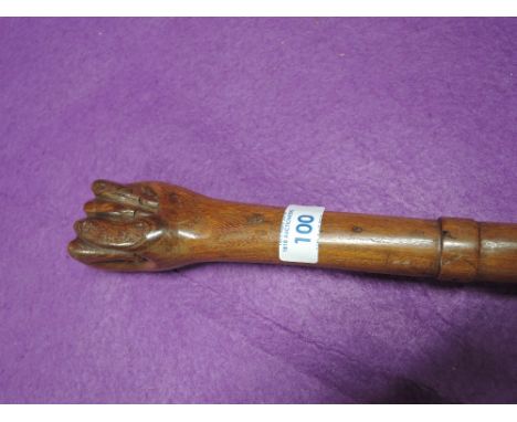 A vintage walking stick or cane in hand carved wood with human fist style handle