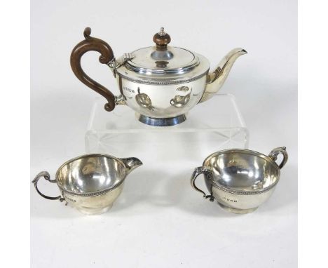 An early 20th century silver three piece tea service, of circular shape with a foliate rim, comprising a teapot, with a woode