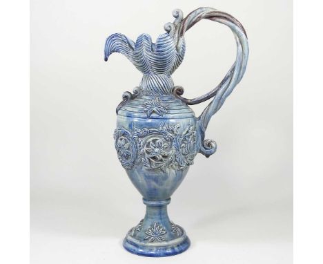 A Castle Hedingham blue glazed pottery ewer, with a twisted scrolled handle, decorated in relief with foliate designs, pad ma