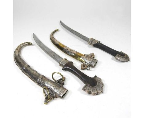 An early 20th century Middle Eastern dagger, with a metal mounted wooden handle and curved steel blade, in a brass scabbard, 