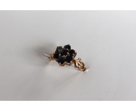 A 9ct gold sapphire cluster ring, set with seven sapphires to a floral setting on a 9ct yellow gold setting and shank, size K