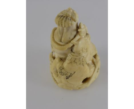 An Antique Carved Ivory Netsuke, with character marks to base, the netsuke depicting a woman with a male character clinging t