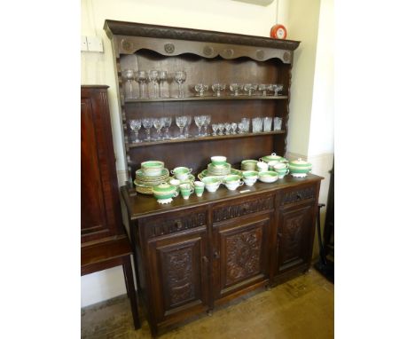 An Antique Stained Oak Dresser, three short drawers with three cupboards beneath, two plate racks, with decorative carving to