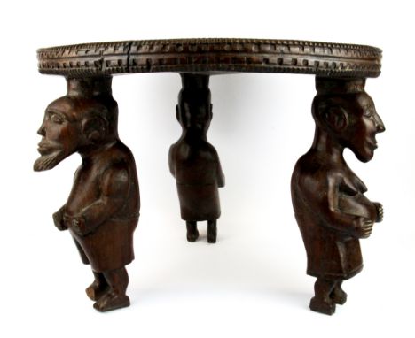 A rare African carved tribal hardwood table/stool with figural legs carved from a single piece of trunk, Dia. 47cm H. 34cm.