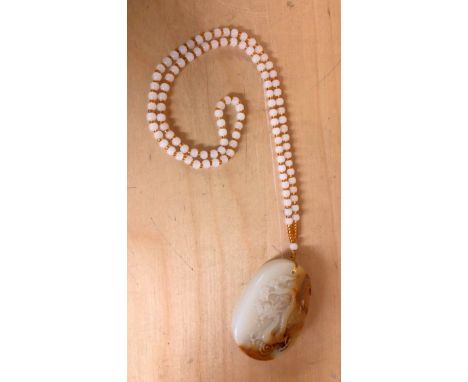 A Chinese carved mutton fat and russet jade dragon amulet on a strand of polished white jade carrying beads, amulet H. 6.5cm.