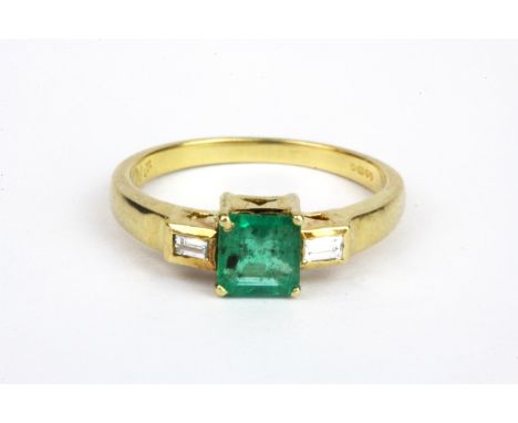 An 18ct yellow gold ring set with an emerald cut emerald and baguette cut diamond set shoulders, (L).