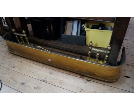 An antique brass fire kerb, 121cm wide; together with a pair of brass andirons; and a set of three brass fire tools. 