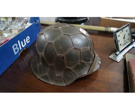 A German World War II helmet, with wire camouflage decoration, the interior inscribed 'Oscha Holzel'.