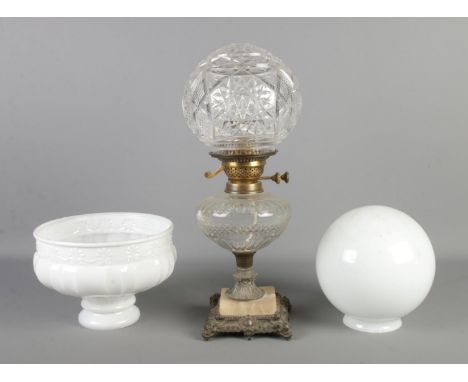 A decorative glass bodied oil lamp (converted to electric), raised on stepped base, together with two additional globes.  Nib