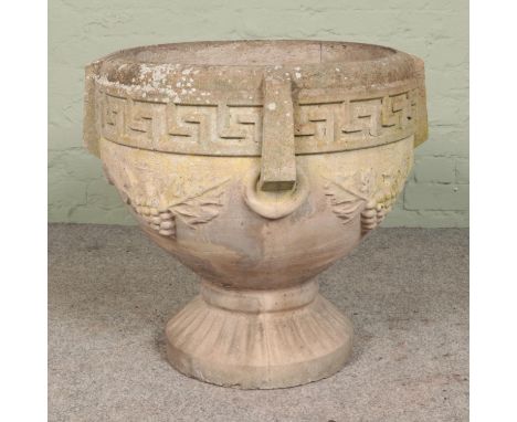 A heavy cast concrete garden urn, with grape and leaf decoration and Greek key border. Diameter of bowl: 54cm. Height: 64cm. 