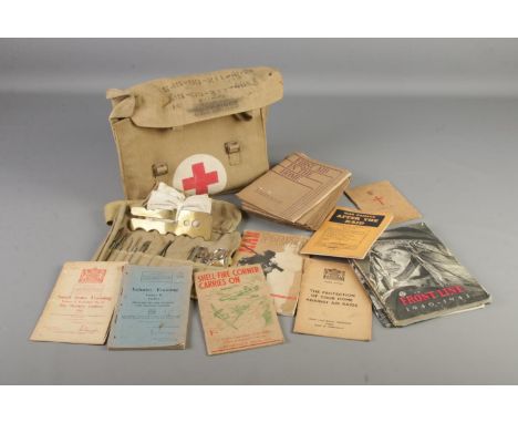 A military first aid medical bag with medical instruments and various booklets including first aid for your home and war dama
