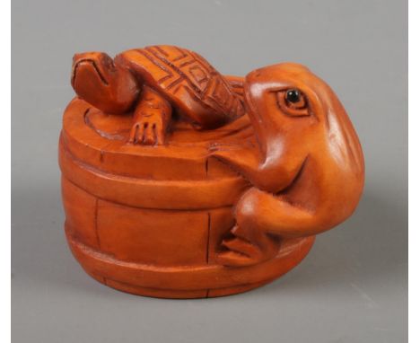 A Japanese carved Netsuke in the form of a turtle and a frog in a barrel.  
