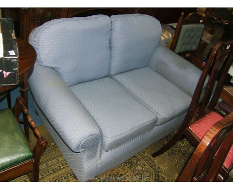 A modern small two seater Sofa with scroll arms in pale blue, shadow geometric pattern fabric upholstery.