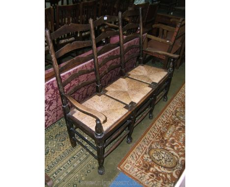 A Clisset style three seat, ladder back Bench Seat with three sets of five ring ladder backs, three rush drop-in seats, on sh