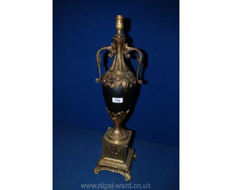 An ornate Brass and black china Table Lamp with pierced foliage decoration standing on a square brass plinth with four scroll