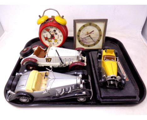 A tray of three Burago die cast classic cars together with a Mickey Mouse alarm clock and a further mid century clock 